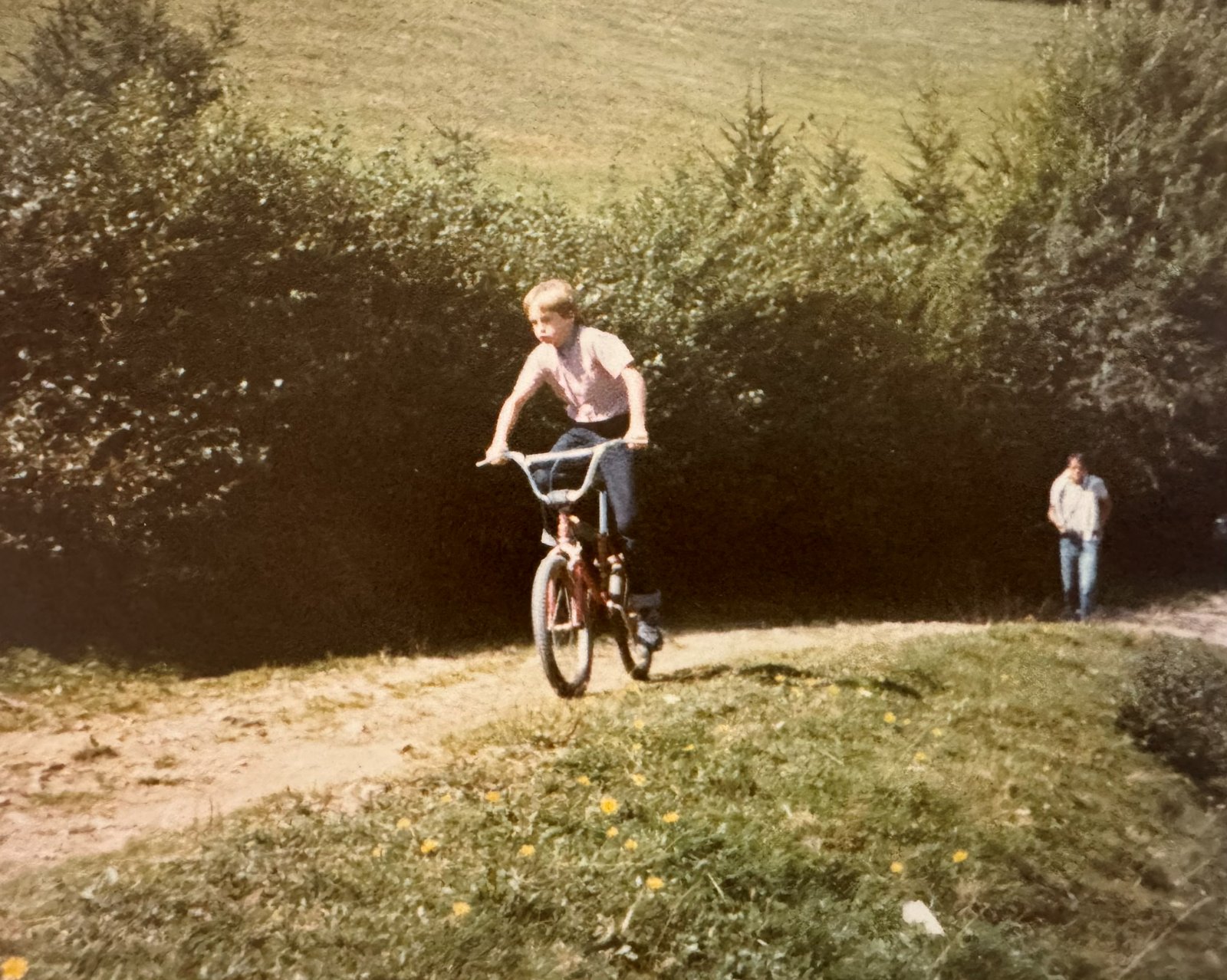 Christian fährt als Kind mit dem BMX einen Feldweg entlang